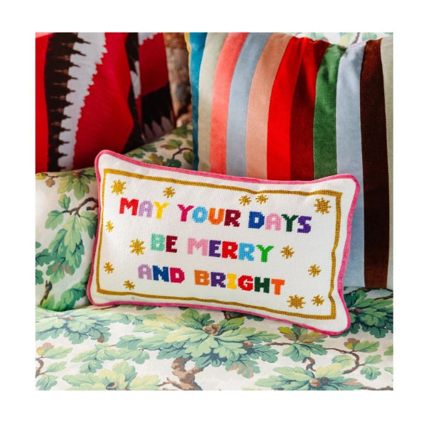 Decorative pillow with 'May your days be merry and bright' text on a floral-patterned surface.
