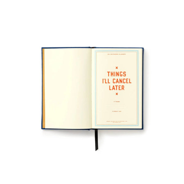 An open hardcover notebook or journal on a white background, showing an unlined cream page on the left and a printed page on the right with the orange text 'THINGS I'LL CANCEL LATER' and a thin blue border. The notebook has a dark blue cover and a black ribbon bookmark.