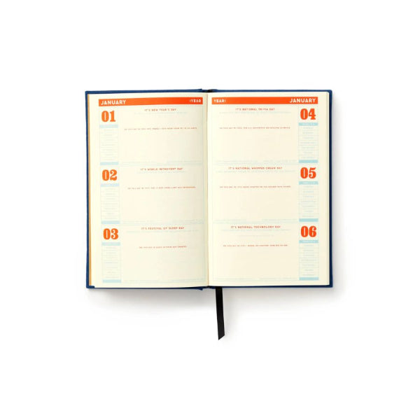 An open weekly planner with cream-colored pages, orange and blue headers, and a black ribbon bookmark, displayed on a clean white background.