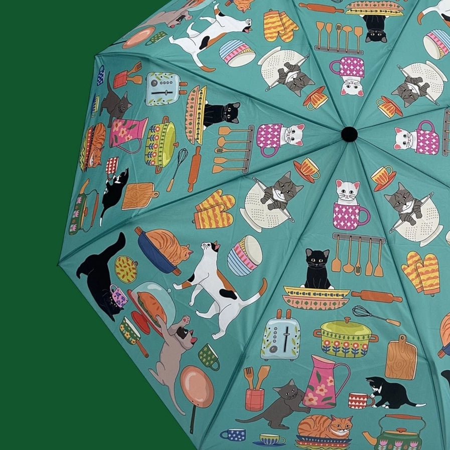 Umbrella with colorful kitchen-themed pattern featuring animals and utensils on a green background