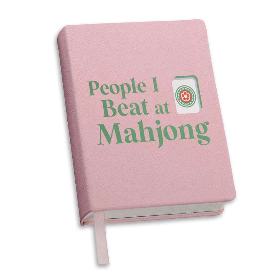 Pink notebook with 'People I Beat at Mahjong' text and a logo on a white background