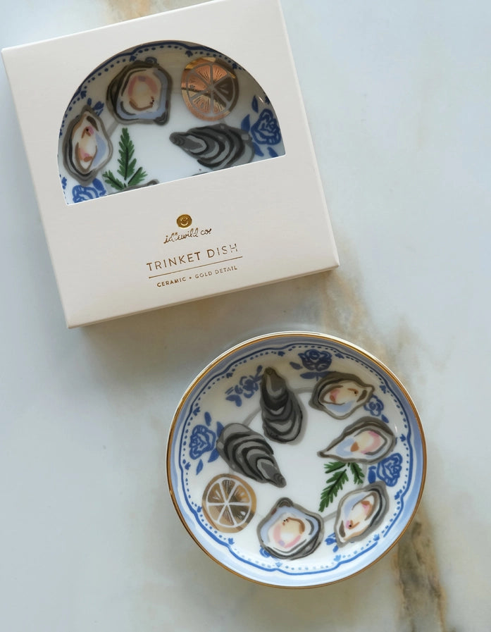 Decorative ceramic dish with oyster design and packaging on a marble surface