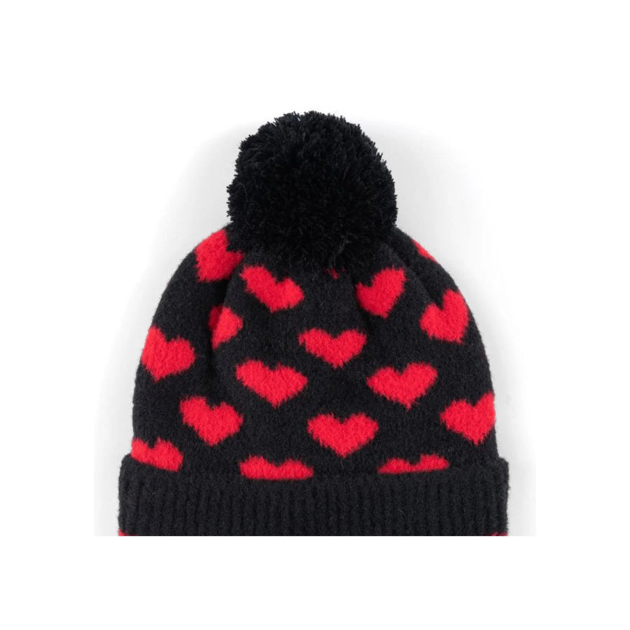 Black knit beanie with red heart pattern and black pom-pom on a white background
