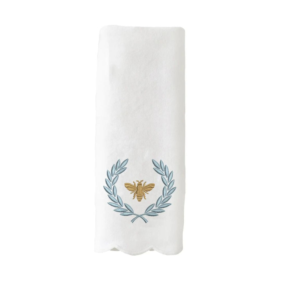 White hand towel with a embroidered design of a bee and laurel wreath on a white background